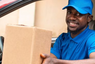 Modern post and delivery by car. Courier looks at tablet and hol